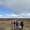 photo of a group of four people carrying river sampling equipment across a moorland