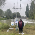A man standing by an eddy tower in the foreground. The Thames River in the background.