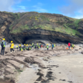 Photograph of a large group of students in high-vis gear working on a large beach