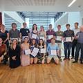 Group photo of academic award winners at their presentation, each holding their certificate, alongside the prize sponsors