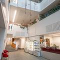 Photograph of the Department Atrium. There is a large space with a reception desk and display cabinets, and three upper floors open to the space. The walls are painted white and the floor is a dark grey.