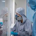 Photograph of two researchers in the clean suite. They are wearing protective gear and face masks.