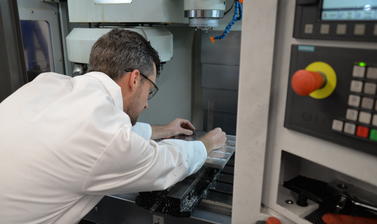 Workshop manager adjusting something inside a piece of machinery