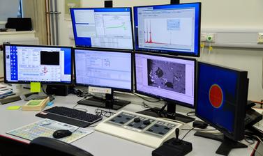 Computer system for the CAMECA SX-5 FE is shown on a table in the E-Beam Suite in the Earth Sciences Department. Control panels are also on the table. 