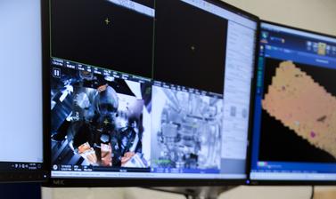Control panel for image analysis sits on table below the Thermo Scientific Apreo 2 SEM computer system located in the Oxford Materials Department. Live feed from inside SEM and sample analysis are shown on the screens. 