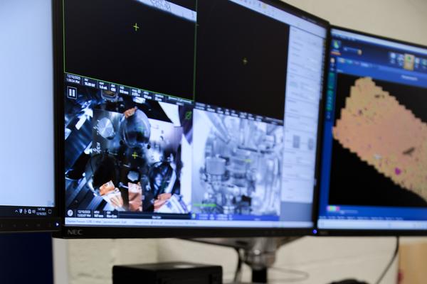 Control panel for image analysis sits on table below the Thermo Scientific Apreo 2 SEM computer system located in the Oxford Materials Department. Live feed from inside SEM and sample analysis are shown on the screens. 
