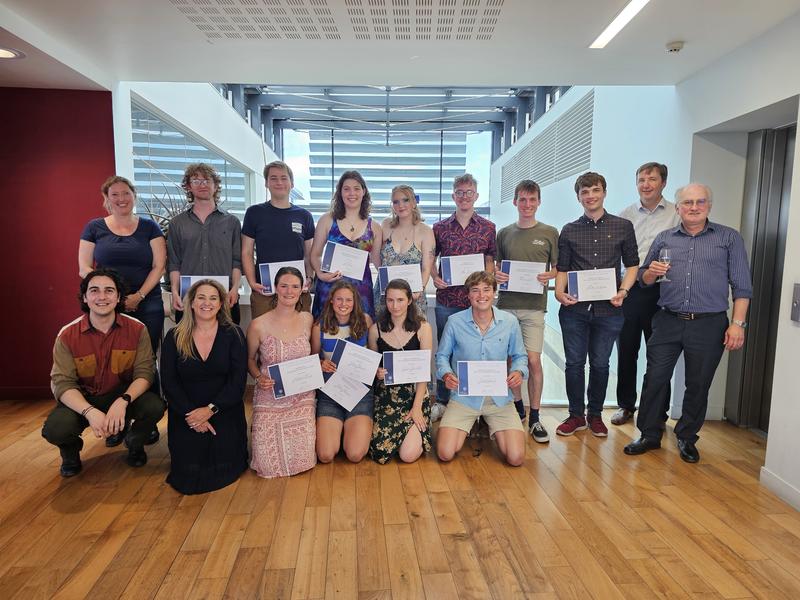 Group photo of academic award winners at their presentation, each holding their certificate, alongside the prize sponsors