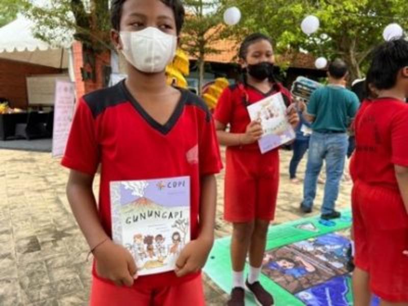 A young boy and girl holding copies of the COPE volcano book 