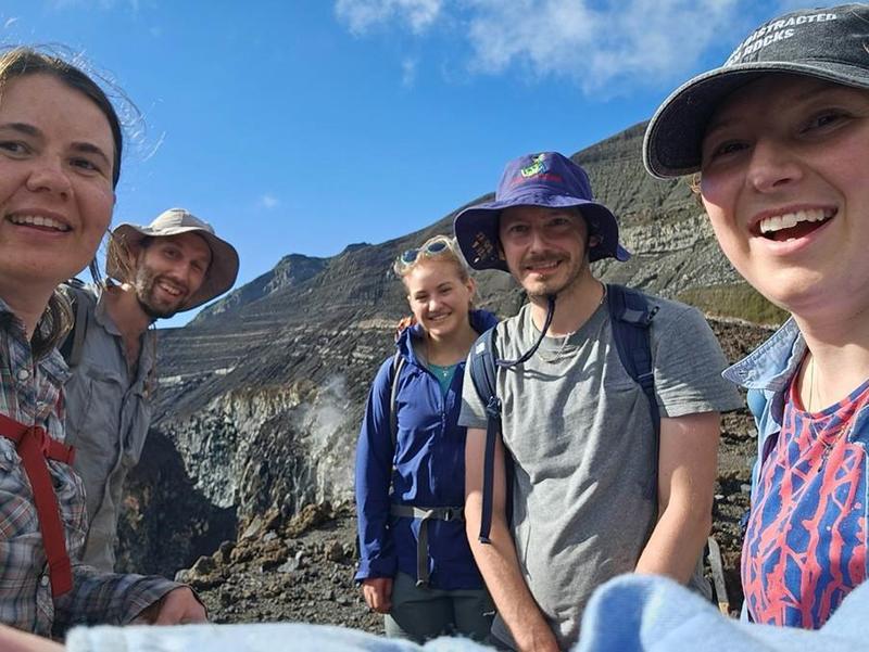 Group photograph of scientists smiling at the camera in the crater of a volcano
