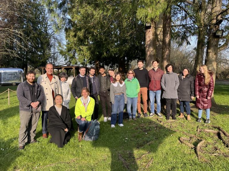 A photo of a group of around 15 people, one of them Ros, standing on some grass with some trees behind them 
