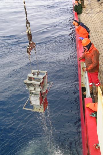 Box corer being deployed off the side of an ocean vessel to collect marine samples