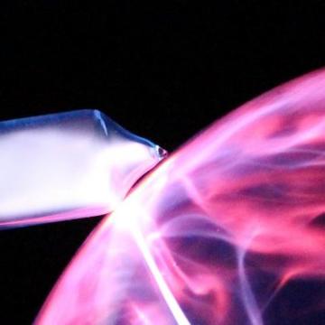 The top left corner of a pink and purple ball of gas on a black background. It is emitting some white light.