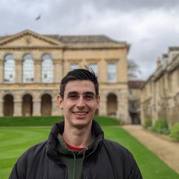 A headshot of Victor Vescu in front of a college quad