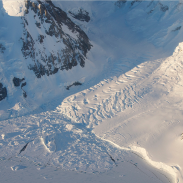Ice sliding down a snow covered mountain in Antarctica 