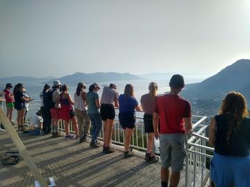 Students on the Greece Field Class 4 Photograph of students relaxing on the Greece field class, overlooking a viewpoint, with their backs to the camera.
