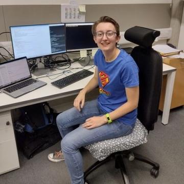 A photo of Rebecca sitting on a desk chair in front of a computer 