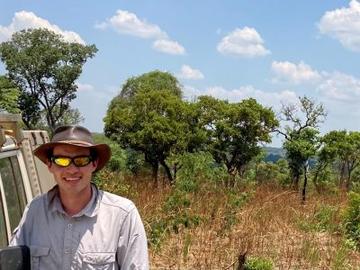 Toby Photo A picture of Toby wearing a hat standing next to a car in a grassland with trees behind him