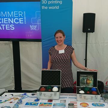 Image of Paula Koelemeijer stood at a display of 3D printed materials discussing seismology. The text "3D printing the world" is displayed