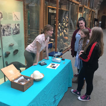 Photograph of Erin Saupe talking to members of the public at a display in a museum