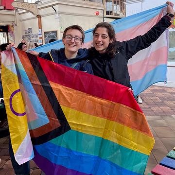 Rebecca Colquhoun and Hannah Sanderson holding a pride flag and a trans pride flag