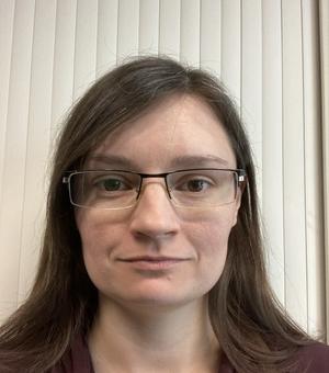 Passport style photograph of Claire Rylatt. She is wearing glasses and has long brown hair.